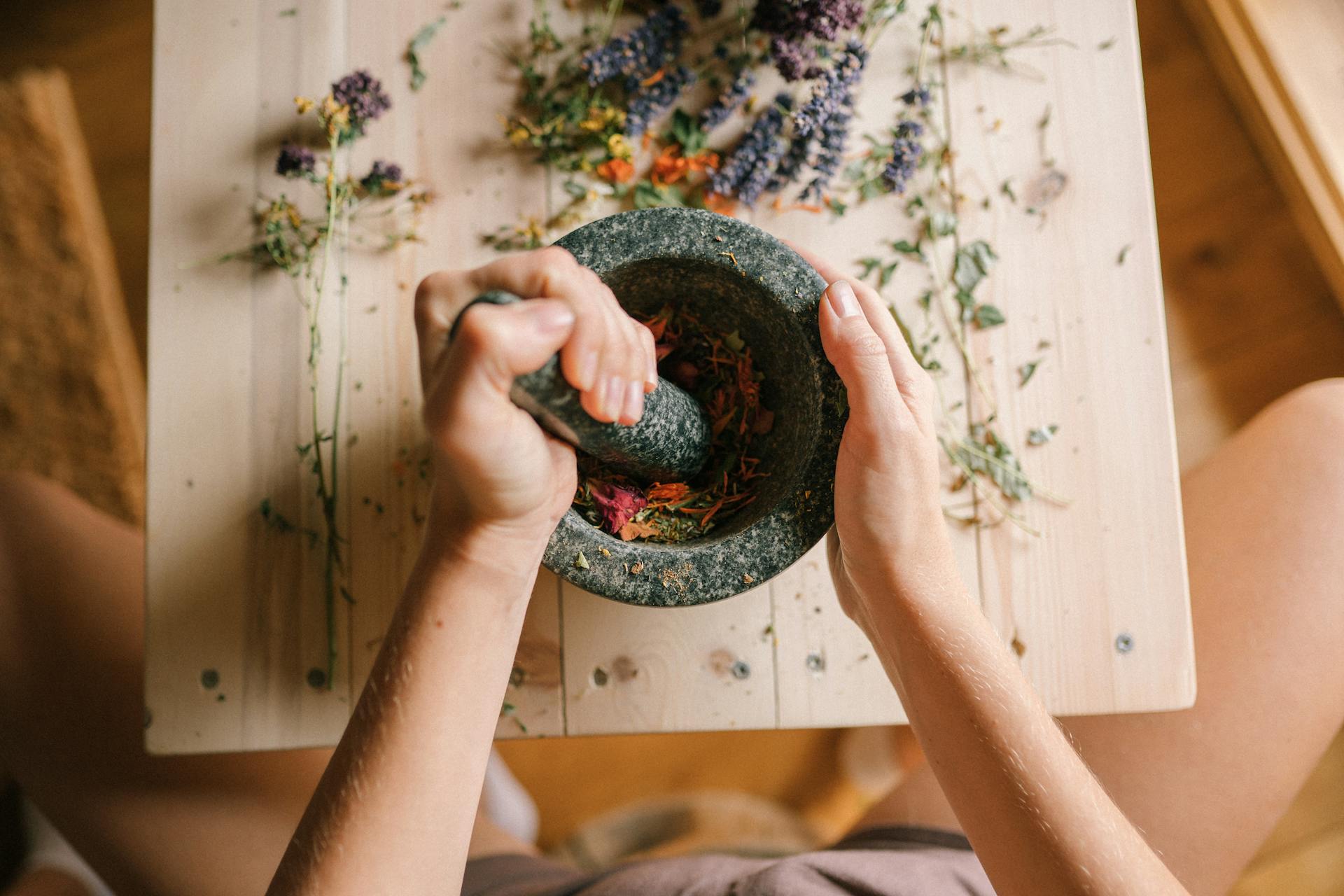 A Person Pounding Dried Flowers Using a Mortar and Pestle