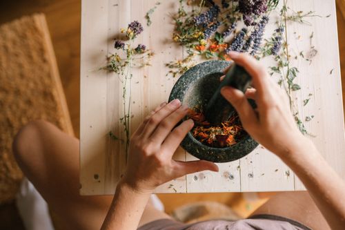 Free Top view of hands using a mortar and pestle to grind herbs on a wooden surface. Stock Photo