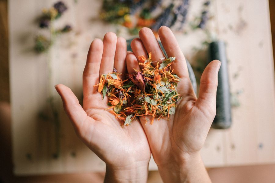 Hands holding a mix of dried herbs over a wooden surface
