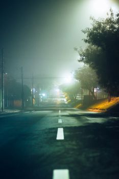 雾气缭绕的夜色中，巴西一条空荡荡的路灯下道路，营造出一种神秘的氛围