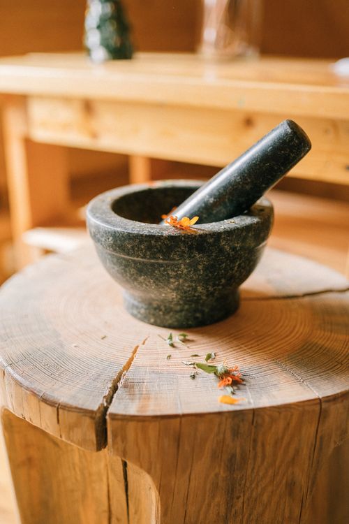 Free A rustic stone mortar and pestle with herbs on a wooden stump indoors. Stock Photo