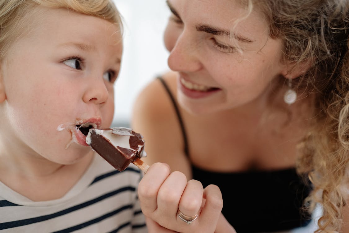 Woman in Black and White Stripe Tank Top Eating Chocolate