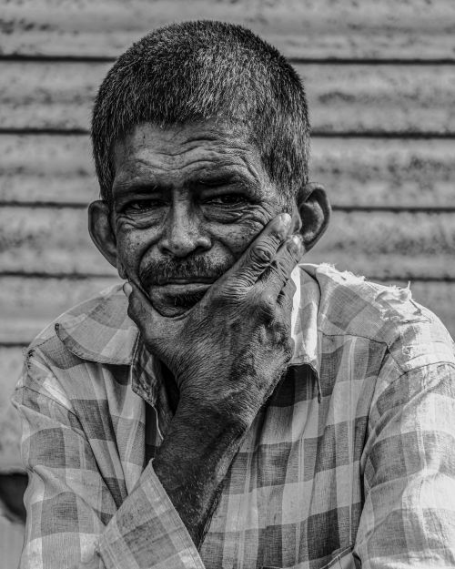 Free A black and white portrait of an elderly man in a contemplative pose, highlighting deep wrinkles. Stock Photo