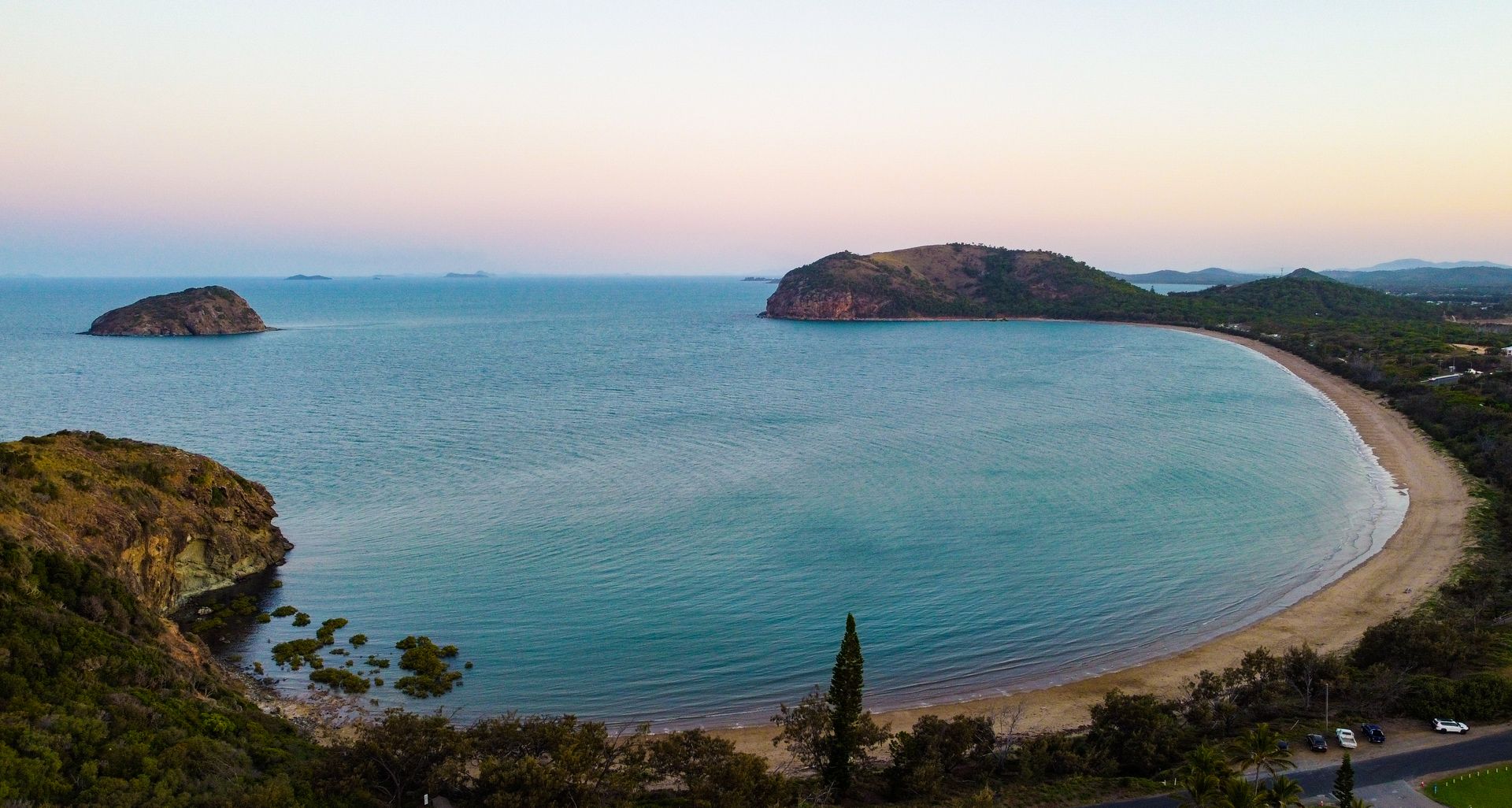 Explore the serene beauty of Rosslyn Bay in Queensland, Australia, captured in a breathtaking aerial view at sunset.