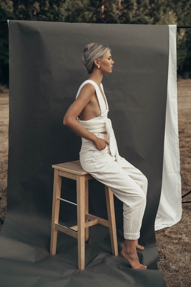 Stylish Woman Sitting Near Gray Textile