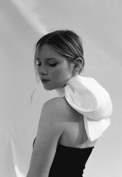 一位年轻女子身着时尚风格的白围巾，优雅的黑白肖像