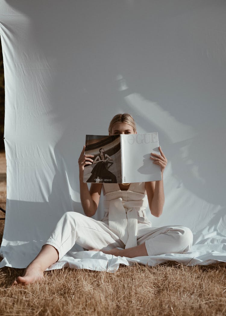 Unrecognizable Woman Reading Magazine In Nature