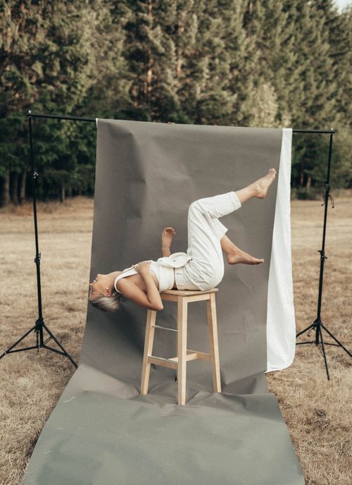Free Full body of barefoot female lying on stool with raised legs on gray background in nature with trees in summer day Stock Photo