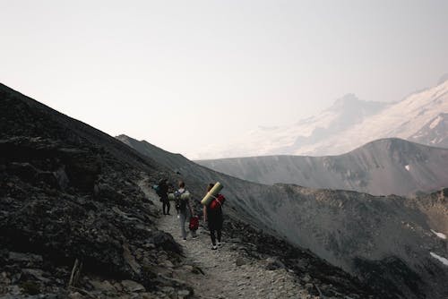 Unrecognizable travelers walking on rocky slope