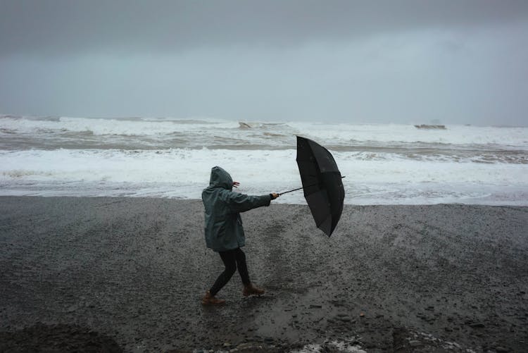 Unrecognizable Person With Umbrella On Beach