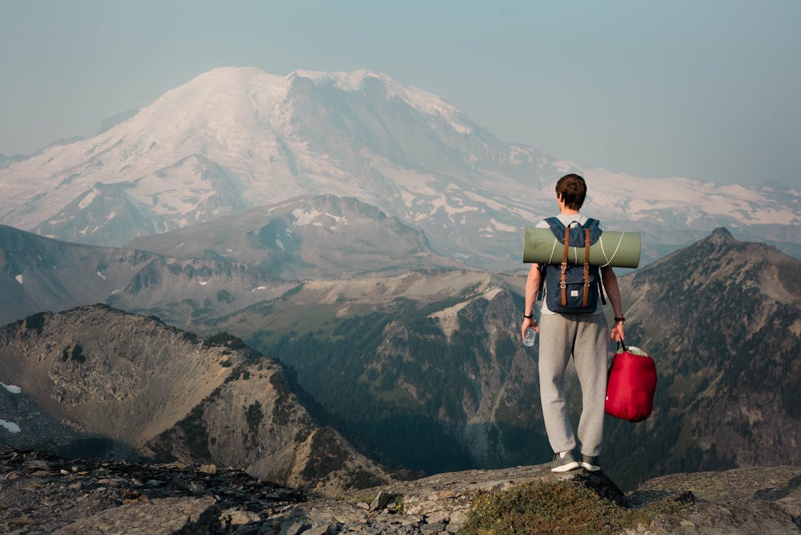 Free Unrecognizable backpacker standing on top of mountain Stock Photo