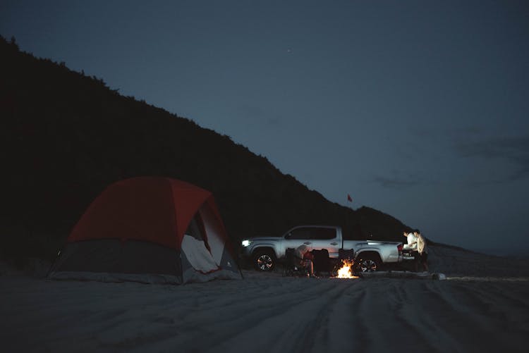 Unrecognizable People On Beach With Camping Tent