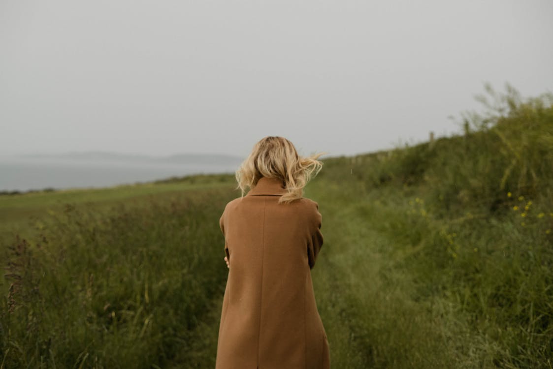 Anonymous woman walking in cold field
