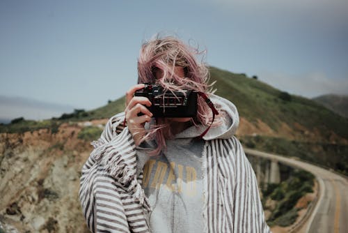 Woman in plaid taking photo in mountains
