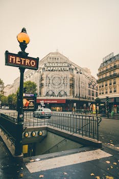 Discover the iconic Galeries Lafayette facade in Paris with nearby metro signs on an overcast day. by Margerretta