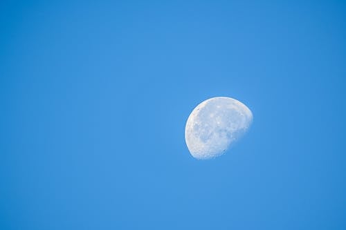 Natural satellite of Earth with craters on bright blue cloudless sky at daylight