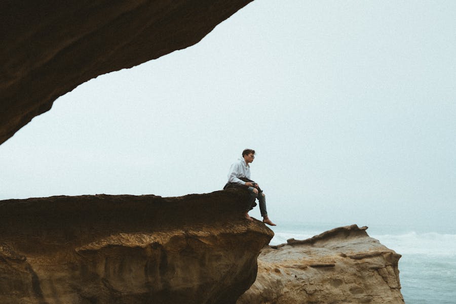 Person sitting alone on cliff above ocean