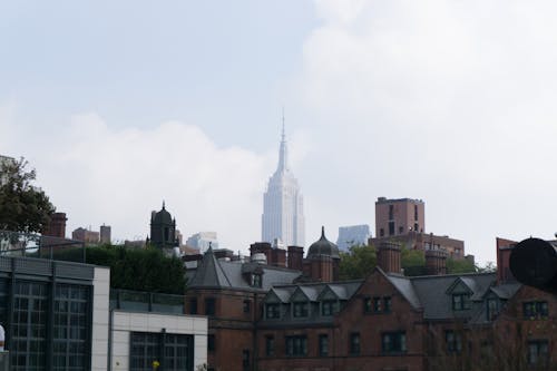 Free Majestic skyscraper tower in cloud above old buildings in district of New York in daylight Stock Photo