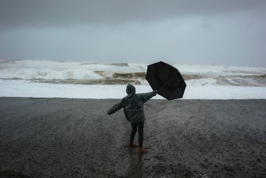 海滩上的人冒着暴风雨，拿着雨伞抵御强大的海浪