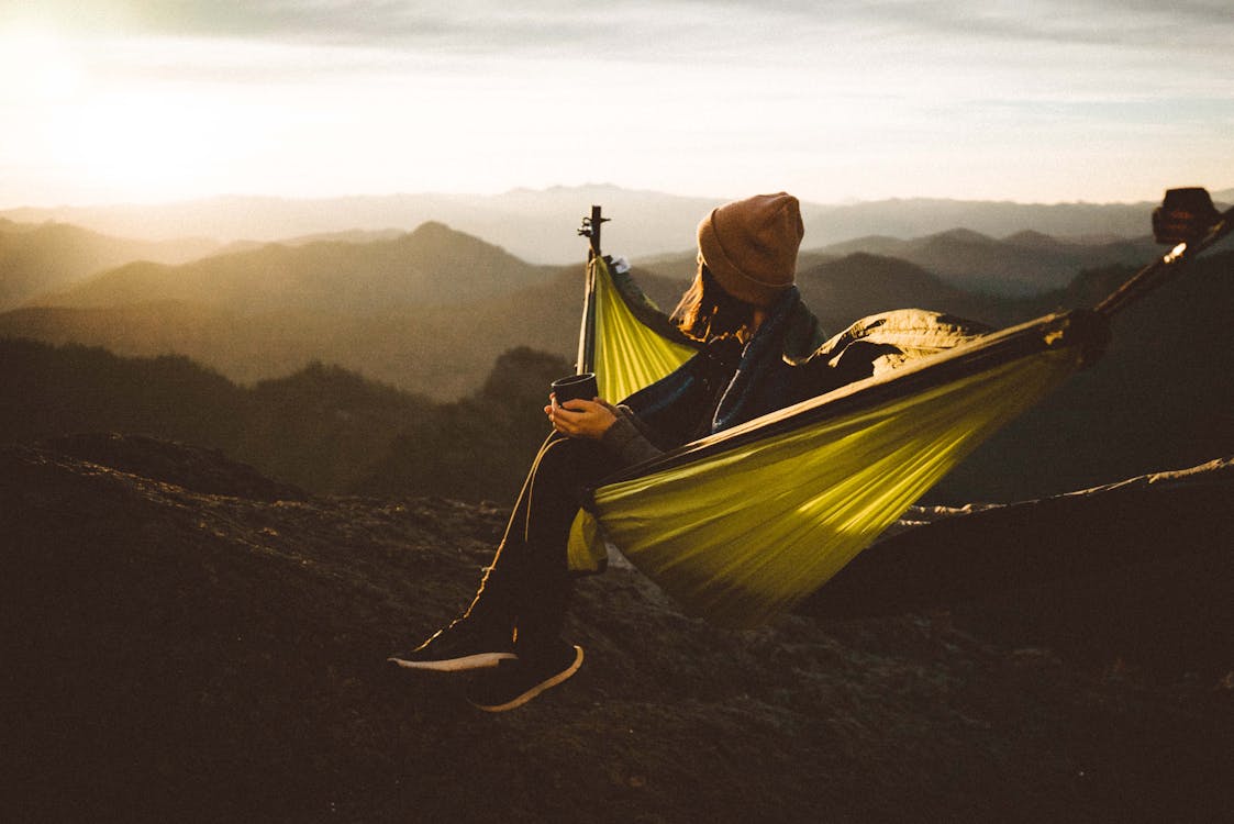 Free Unrecognizable woman sitting in hammock above mountains Stock Photo