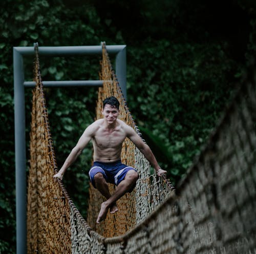 Smiling fit ethnic male athlete on suspension bridge