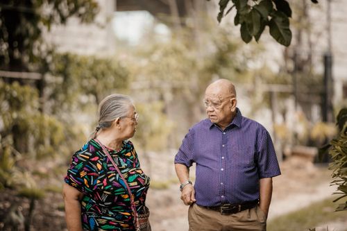 Free Dissatisfied senior woman in ornamental clothes speaking with male partner in eyeglasses while looking at each other on walkway Stock Photo