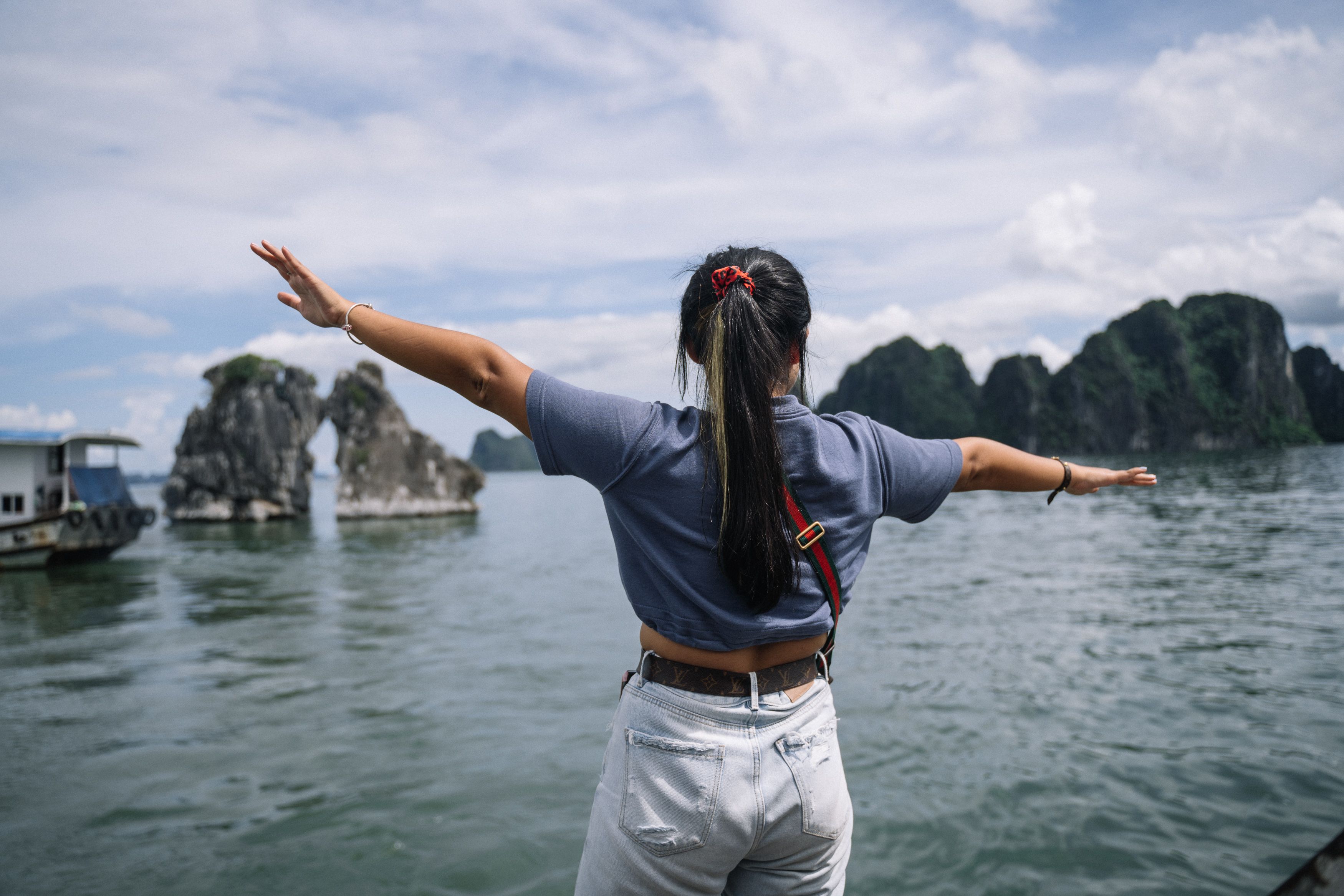 一个女人张开双臂，欣赏着风景优美的海滨景色