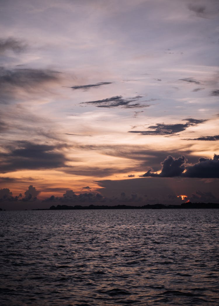 A Mountain Near The Calm Sea During Sunset