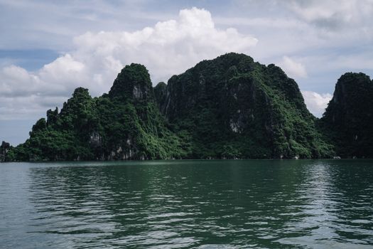 从下龙湾的水域中，郁郁葱葱的绿色石灰岩岩溶地层急剧升起
