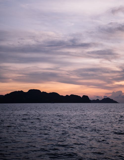 日没時の水域近くの山のシルエット