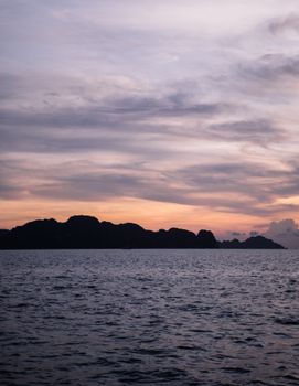 日落时分，平静的海浪映衬着远处黑暗的山影