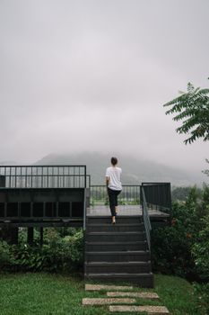 薄雾笼罩的山区中，人站在楼梯上，散发着宁静