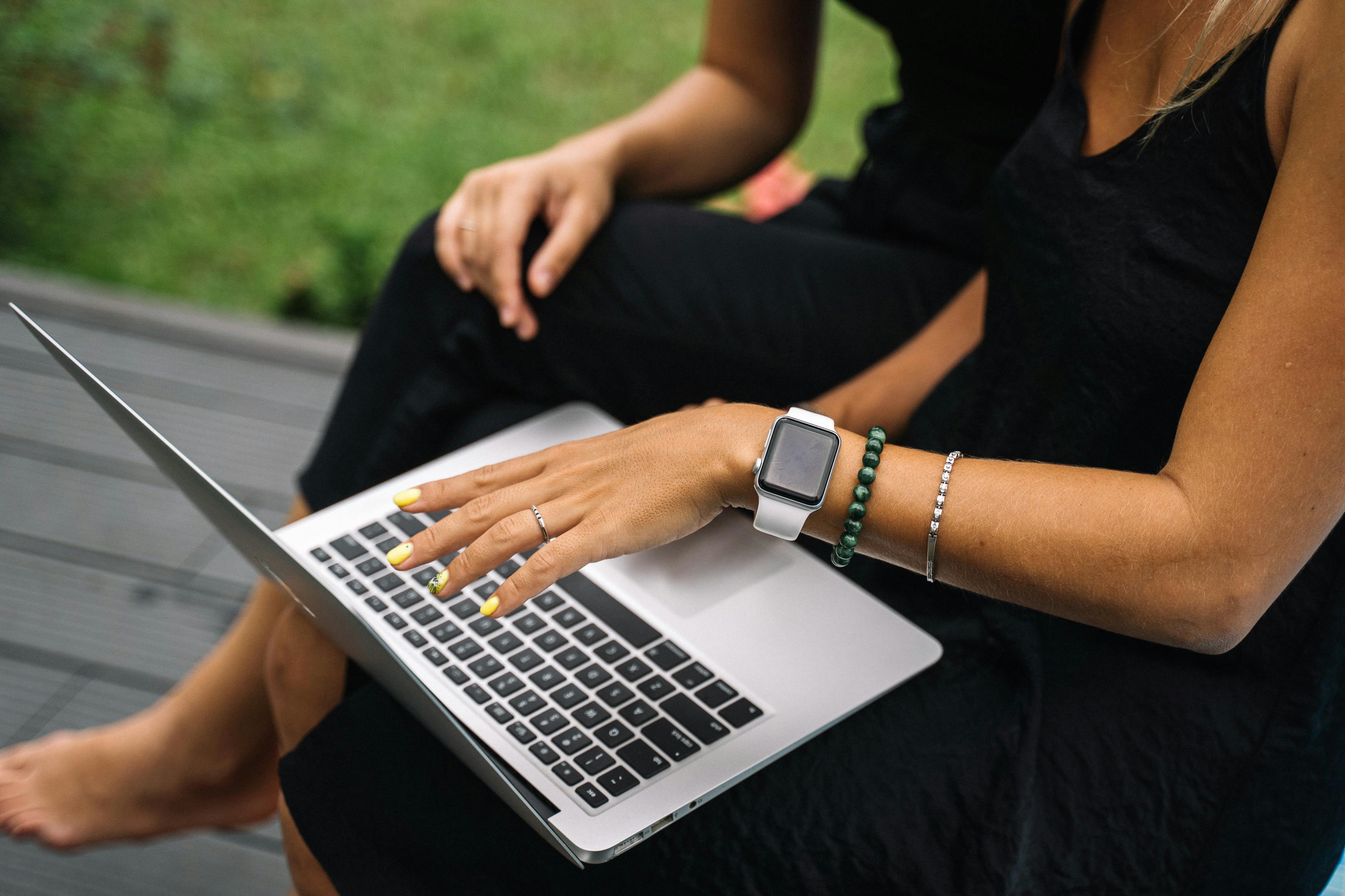 Casual outdoor setting with a woman using a laptop, emphasizing remote work and technology.