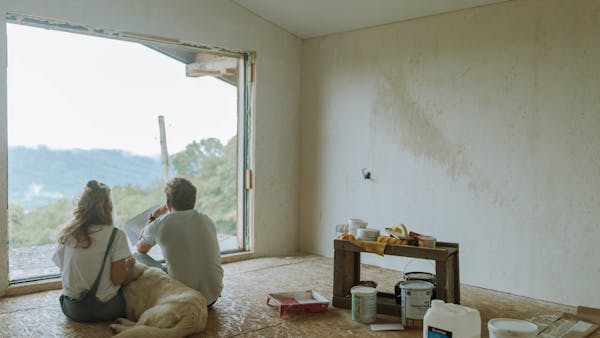 A couple with their dog resting in a partially renovated room, planning the renovation.