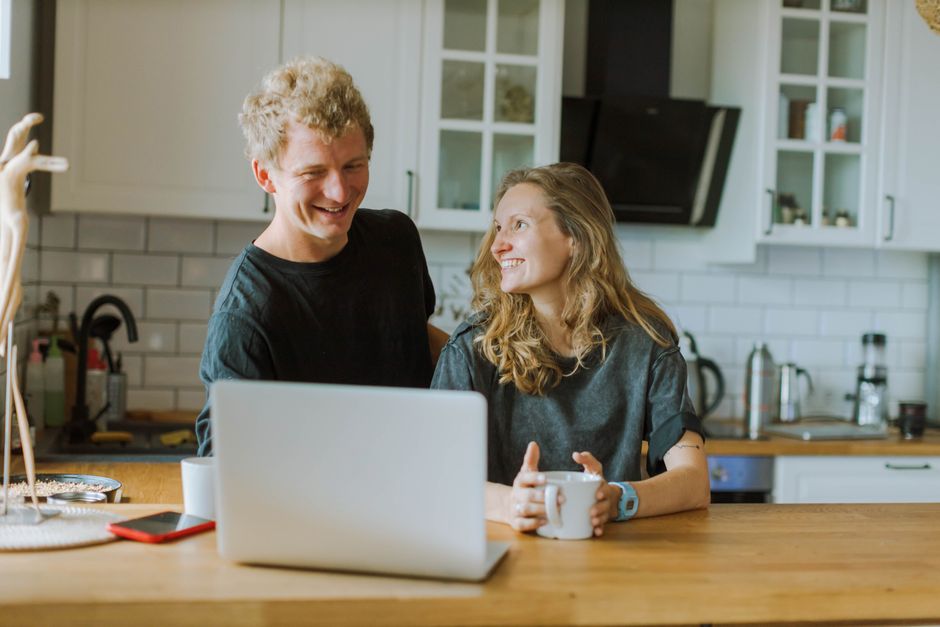A cheerful couple shares a coffee and laughter in their modern kitchen, creating a cozy atmosphere.
