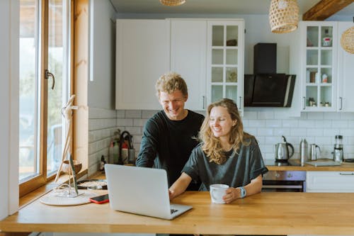 Man and Woman Using a Laptop in the Kitchen Area