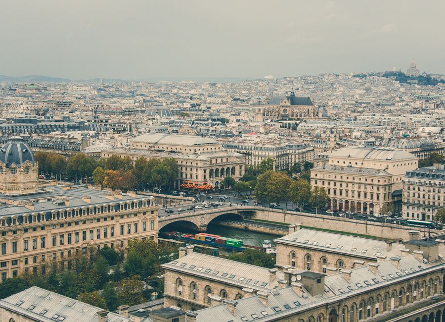 Aerial view of Paris cityscape featuring Seine River and historic architecture under a cloudy sky.