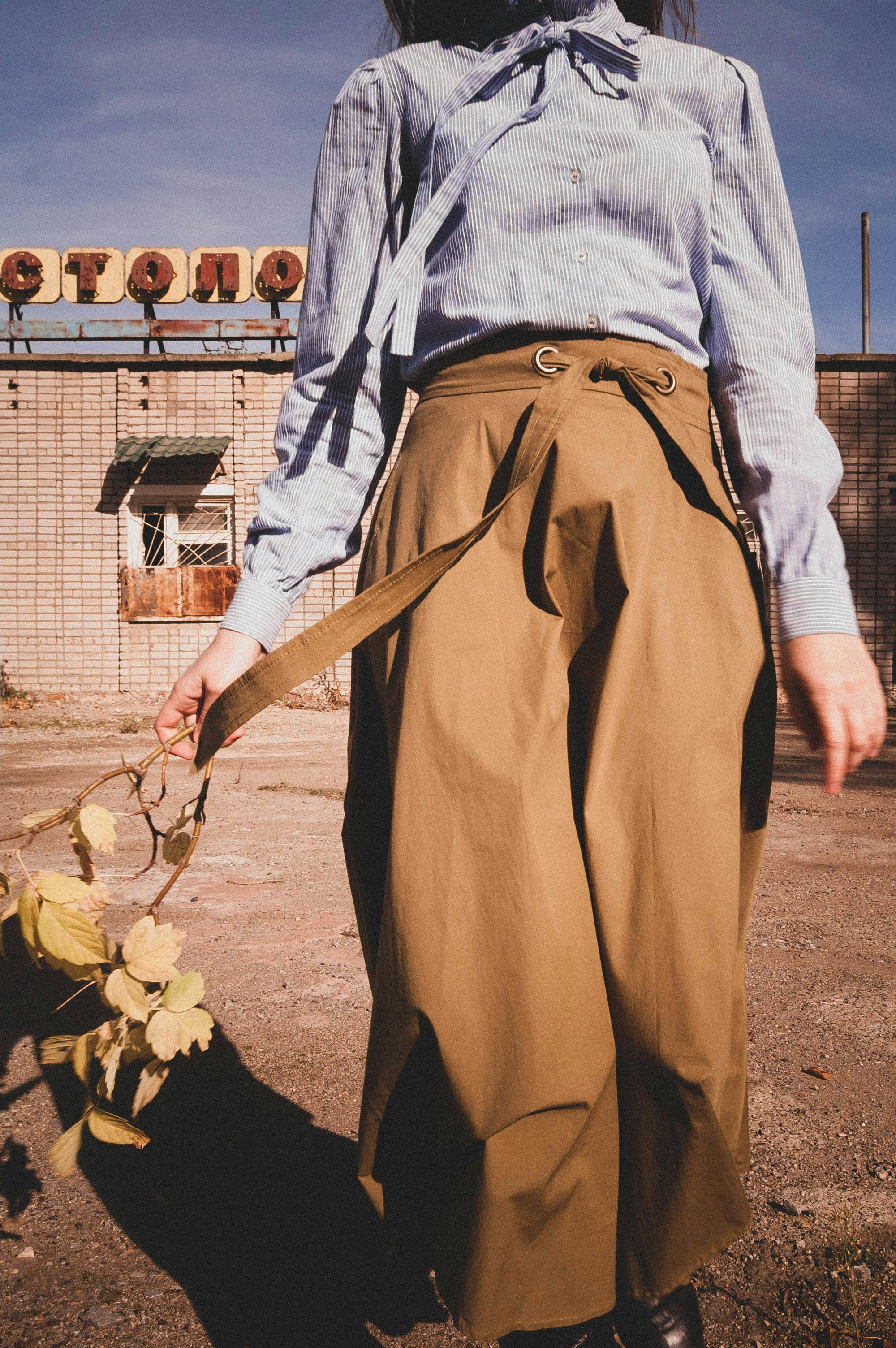 Stylish woman in vintage fashion outdoors holding a branch, exuding a moody Soviet style vibe.