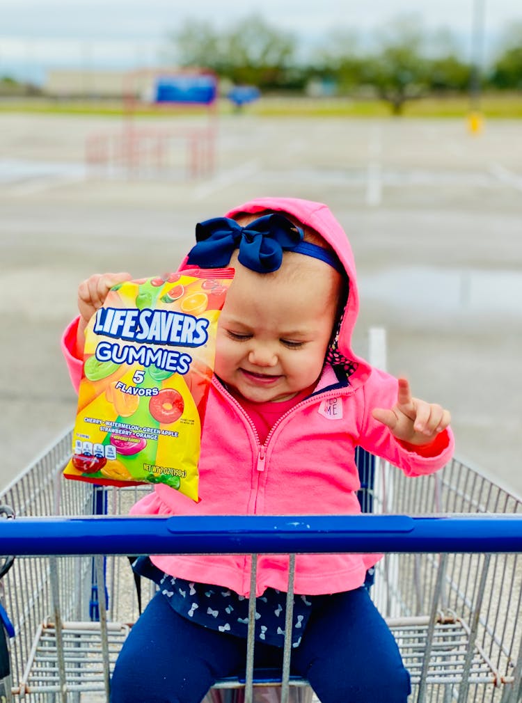 Baby In Pink Jacket Holding Candies