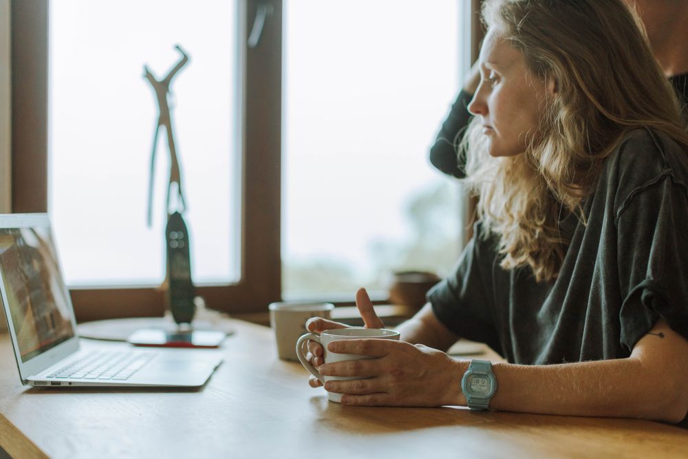 Woman studying at a laptop with a cup of coffee beside her