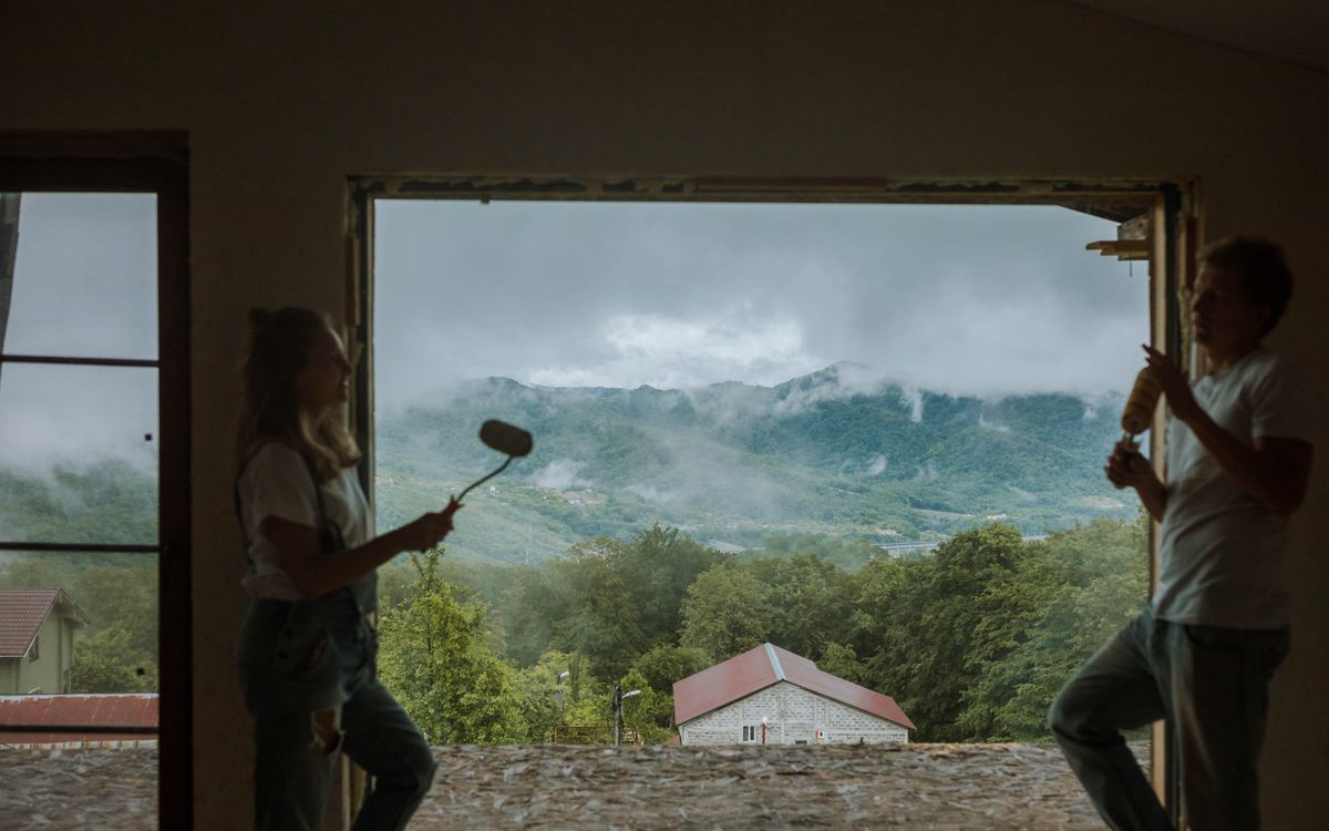 Couple painting and enjoying a scenic mountain view from their home renovation.