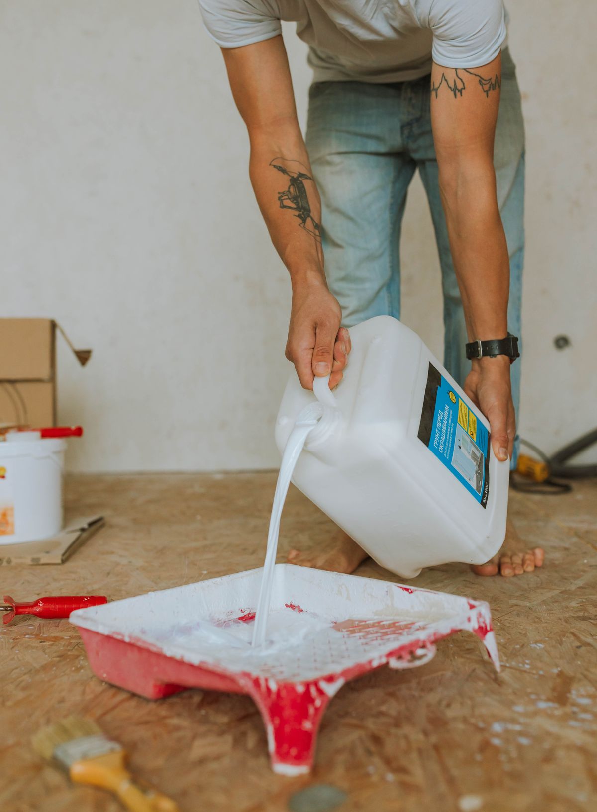 Generic larger coating container being poured into a paint tray