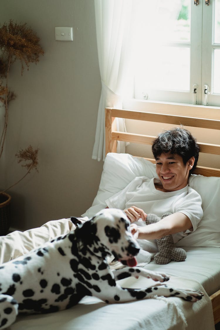 A Man Lying On The Bed With HIs Dog 