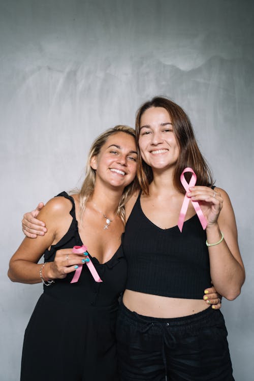 2 Women Smiling While Holding Pink Ribbons