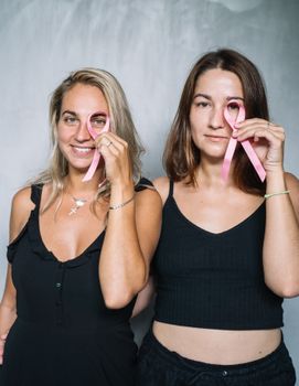 两名妇女手持粉红丝带，以提高对乳腺癌的认识，促进健康