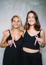 两名妇女手持粉红丝带，通过拥抱来支持乳腺癌防治意识，促进团结