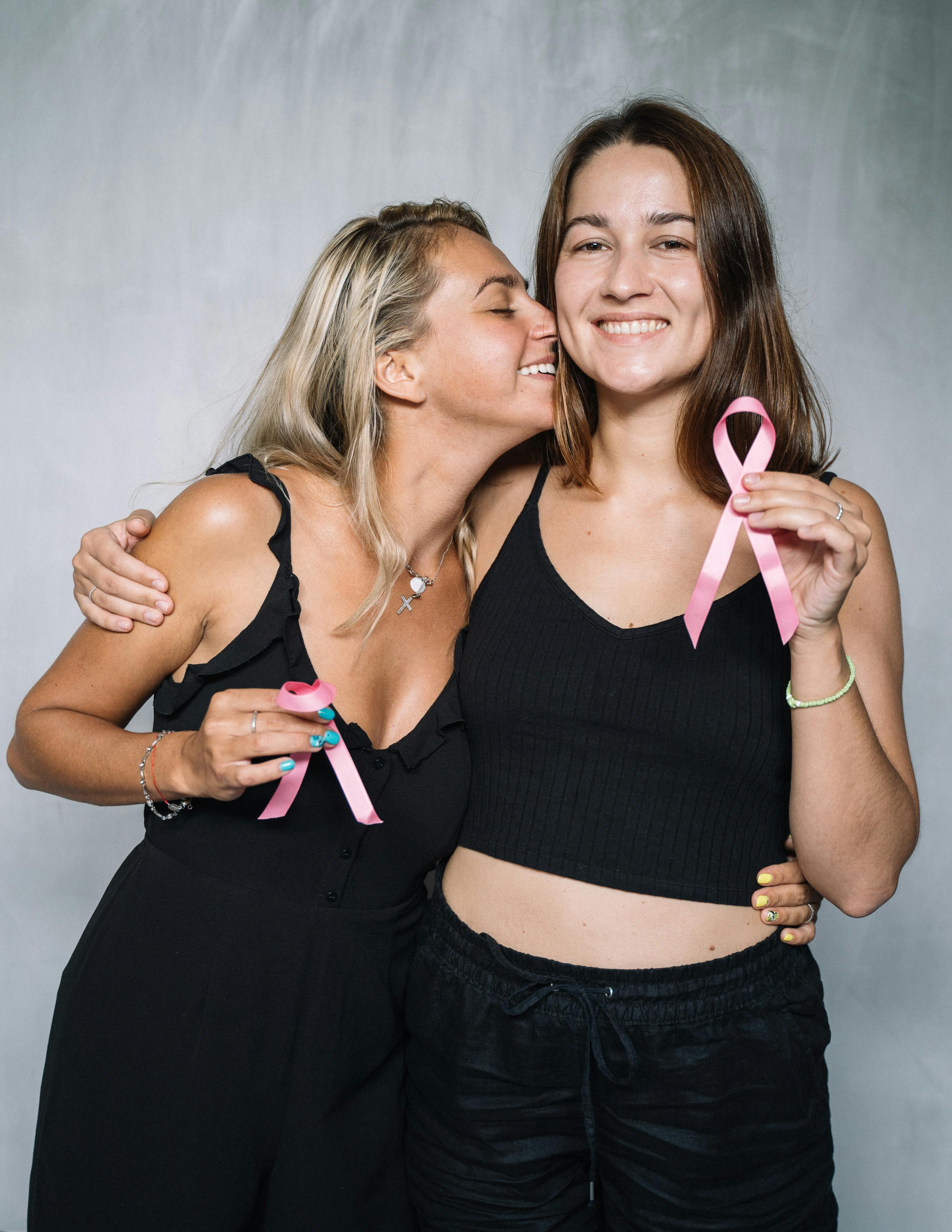 2 women in black tank top holding pink ribbon