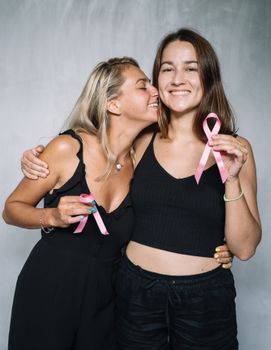 两名妇女用粉红丝带和微笑庆祝乳腺癌防治意识的宣传活动