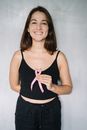一位手持粉红丝带、支持乳腺癌防治的女性微笑肖像