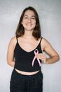 手持粉红丝带的女人微笑着宣传乳腺癌意识